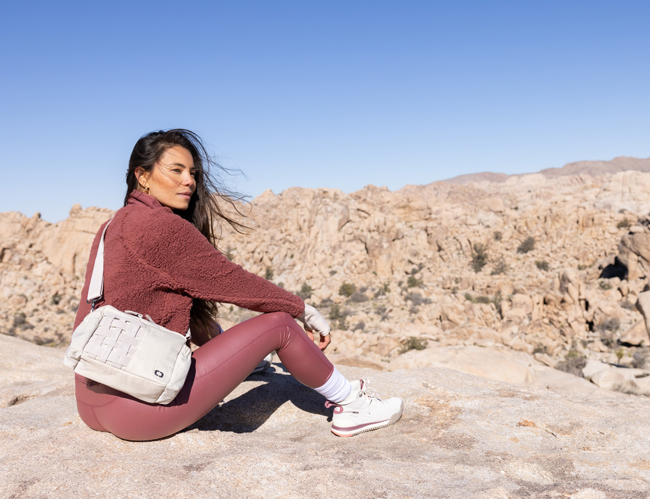 women looking over a rocky desert-scape with a crossbody bag